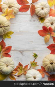 Thanksgiving season still life with small pumpkins and fall leaves over rustic wooden background