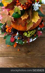 Thanksgiving table centerpiece with fall leaves and seeds, copy . Thanksgiving table centerpiece with autumn leaves and seeds, vertical. Fall background with white flowers, copy space