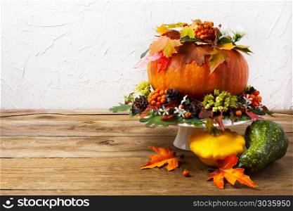 Thanksgiving table centerpiece with pumpkin and yellow squash, c. Thanksgiving table centerpiece with pumpkin, colorful leaves and yellow squash, copy space. Fall greeting background.