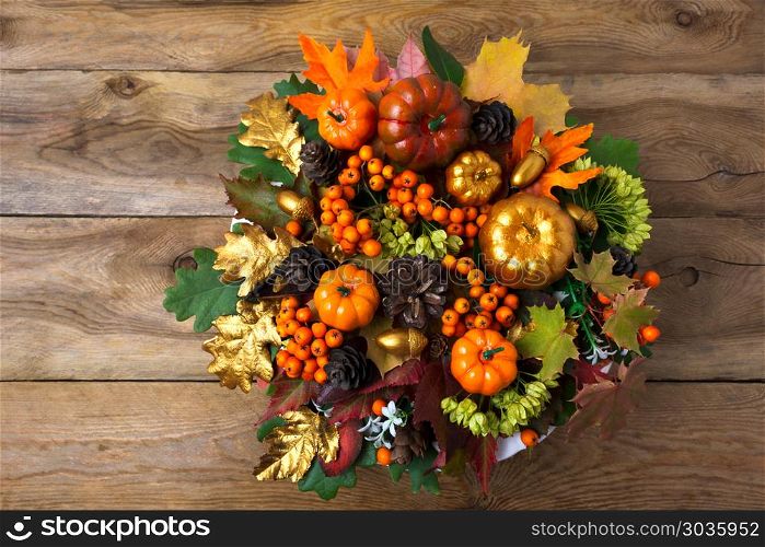 Thanksgiving wreath on the old wooden table. Thanksgiving wreath with pumpkins and autumn leaves on the old wooden table. Fall table centerpiece with berries and cones, copy space