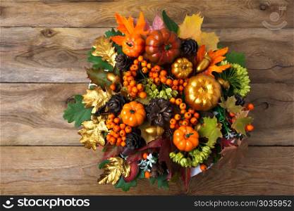 Thanksgiving wreath on the old wooden table. Thanksgiving wreath with pumpkins and autumn leaves on the old wooden table. Fall table centerpiece with berries and cones, copy space