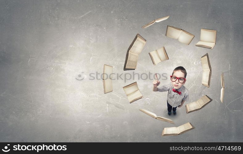 That is interesting point. Top view of cute schoolboy in red glasses with finger up