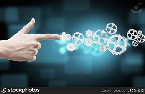 That&rsquo;s how it works. Close up human hand pointing at gears mechanism