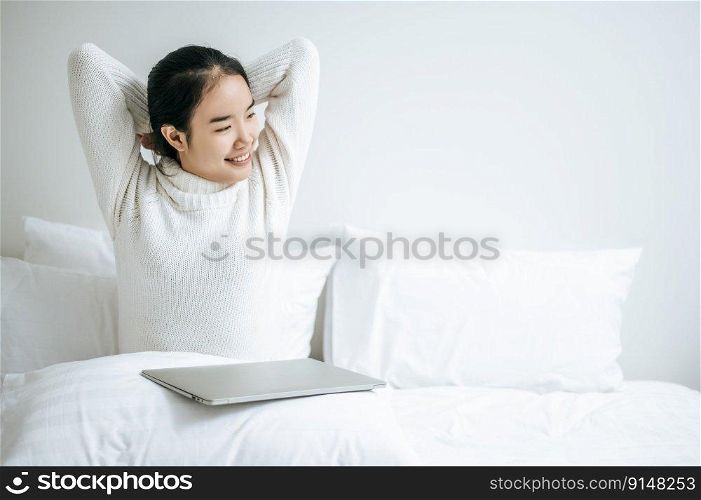 That woman sat on the bed, raised her hand, and put the laptop on the pillow.
