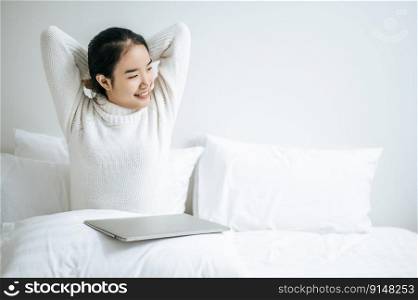 That woman sat on the bed, raised her hand, and put the laptop on the pillow.