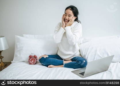 That woman sat on the bed, raised her hand, placed the laptop, and alarm clock.