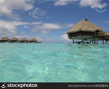 Thatch covered buildings on stilts built in the sea, Moorea, Tahiti, French Polynesia, South Pacific