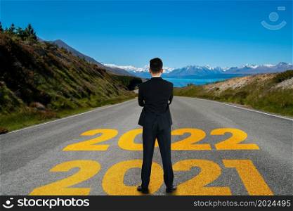 The 2022 New Year journey and future vision concept . Businessman traveling on highway road leading forward to happy new year celebration in beginning of 2021 for fresh and successful start .. The 2022 New Year journey and future vision concept