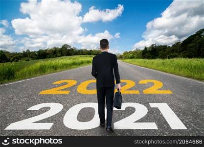 The 2022 New Year journey and future vision concept . Businessman traveling on highway road leading forward to happy new year celebration in beginning of 2021 for fresh and successful start .. The 2022 New Year journey and future vision concept