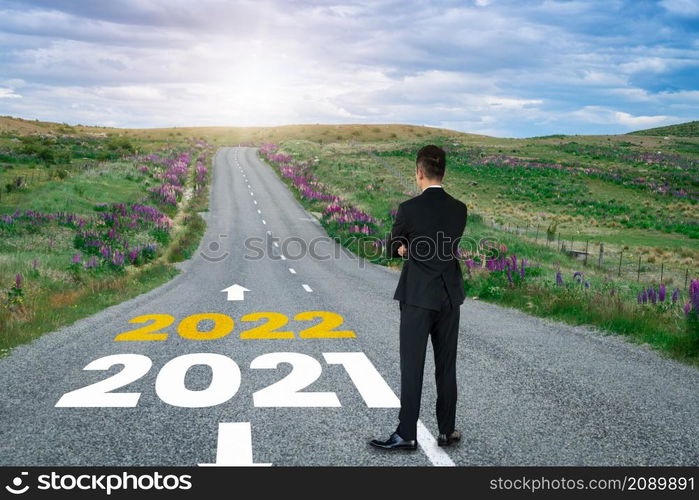 The 2022 New Year journey and future vision concept . Businessman traveling on highway road leading forward to happy new year celebration in beginning of 2021 for fresh and successful start .. The 2022 New Year journey and future vision concept