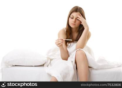 The afflicted girl sits in bed and sees result of the test for pregnancy
