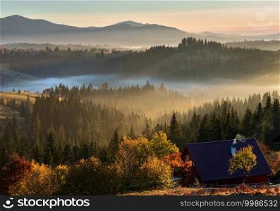 The air. Early morning fog and first morning sun rays over the autumn slopes of Carpathian Mountains and unrecognizable farmstead  Ukraine .