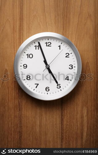 The aluminum wall clock is almost five.