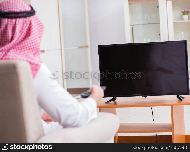 The arab businessman watching tv at home. Arab businessman watching tv at home