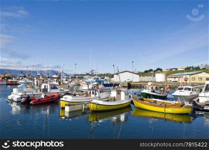 The arctic harbor of Husavik along the Skjalfandi bay, Iceland, with a colorful array of fishing ships, from where tourists are taken on whale watching trips