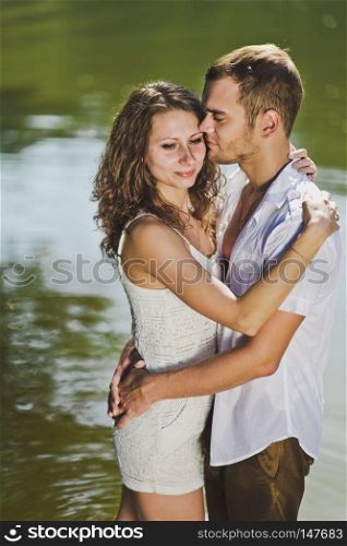 The arms on the background of the greenish water of the pond.. Young guy and girl hugging on nature background 6323.
