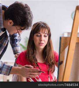 The artist coaching student in painting class in studio. Artist coaching student in painting class in studio