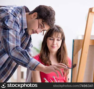 The artist coaching student in painting class in studio. Artist coaching student in painting class in studio