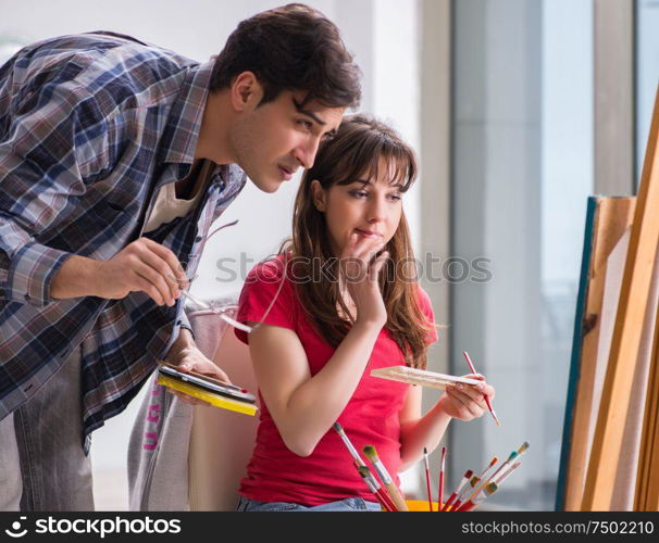 The artist coaching student in painting class in studio. Artist coaching student in painting class in studio