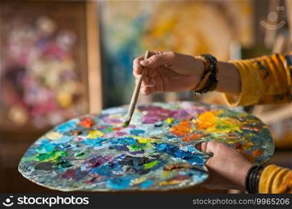 The artist holds a palette in her hand and mixes colors.. A huge palette in the hands of the artist at work 2879.