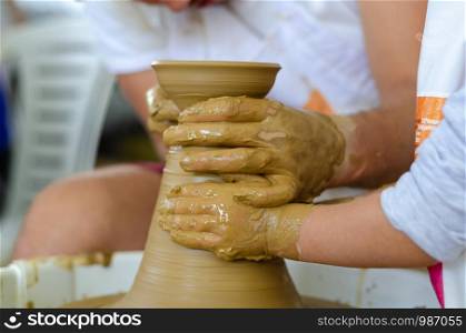 The artist teaches children how to make clay pottery.