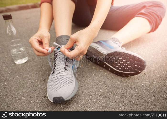 The athlete sits down to the rope of the shoe in the garden and sunset time.