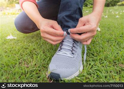 The athlete sits down to the rope of the shoe in the garden and sunset time.