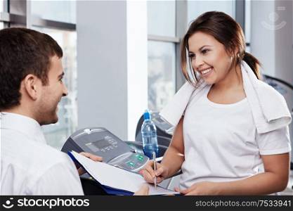 The attractive girl appends the signature in fitness club