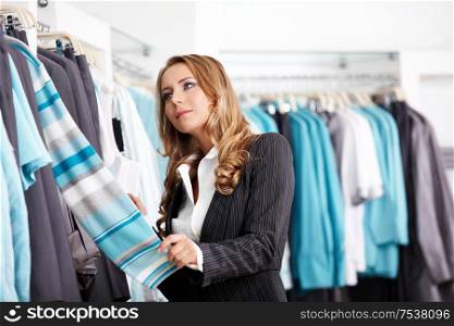 The attractive girl considers clothes in shop