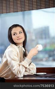 The attractive girl drinks coffee in cafe