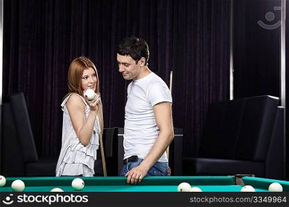 The attractive girl shows to the young man a billiard sphere