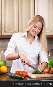 The attractive woman cuts vegetables on kitchen