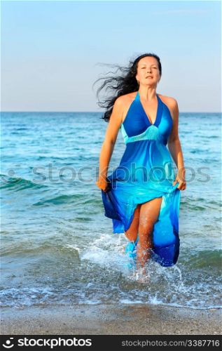 The attractive woman exit the sea. A dark blue dress