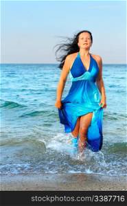 The attractive woman exit the sea. A dark blue dress