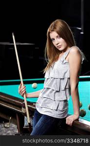 The attractive young girl with cue at a billiard table
