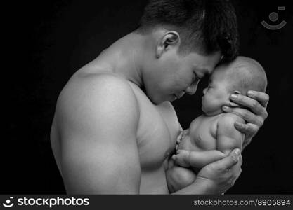 The baby sleeps in the hands of a strong father.