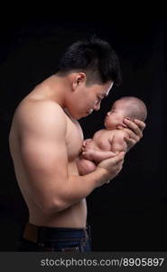 The baby sleeps in the hands of a strong father.