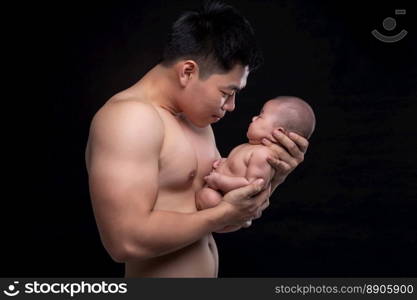 The baby sleeps in the hands of a strong father.