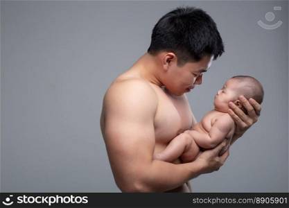The baby sleeps in the hands of a strong father.