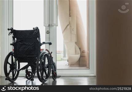 The back of an empty wheelchair with no one sitting as if looking outside through a glass door. Near the exit glass door with a blurred outside view of the garden in background. There is always hope in life, Copy space, Selective focus.
