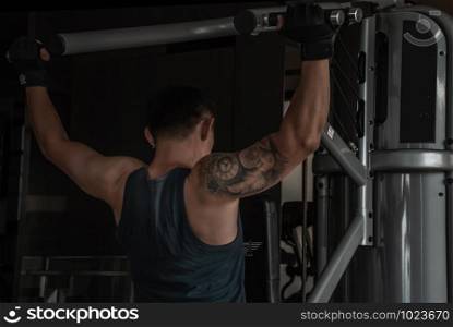 The back of strong male bodybuilder, The power to train muscles with a lifting weights on an exercising machine in gym or fitness club.