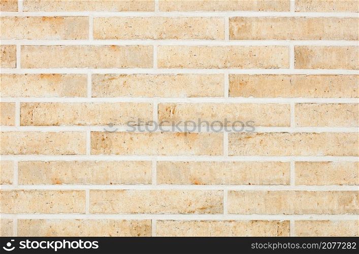 The background and texture of the wall are lined with light beige oblong bricks with scratches and stains in a retro style.. The wall is faced with light beige oblong bricks with roughness. Horizontal execution. Wall texture with smooth cement joints.