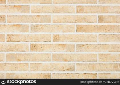 The background and texture of the wall are lined with light beige oblong bricks with scratches and stains in a retro style.. The wall is faced with light beige oblong bricks with roughness. Horizontal execution. Wall texture with smooth cement joints.