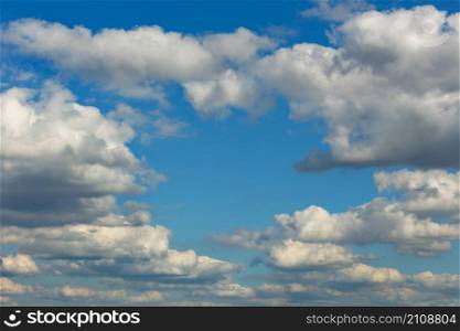 The background and texture of white fluffy clouds floating in a rhythmic row in a semicircle high in the sky, forming a clear window.. Lush white clouds float in height to form a clear window of blue sky.