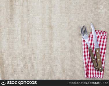 The background for the menu. Canvas tablecloth, fork, knife and napkin for steaks. Is used to create a menu for a steak house.
