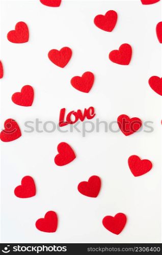 The background which consists of red hearts, the inscription love in the middle of the hearts. Vertical photo. Love concept, greeting card for valentine&rsquo;s day. The background which consists of red hearts, the inscription love in the middle of the hearts. Vertical photo. Love concept, greeting card for valentine&rsquo;s day.