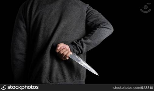 The bandits in the black hold a knife hidden behind on black background. with clipping path.