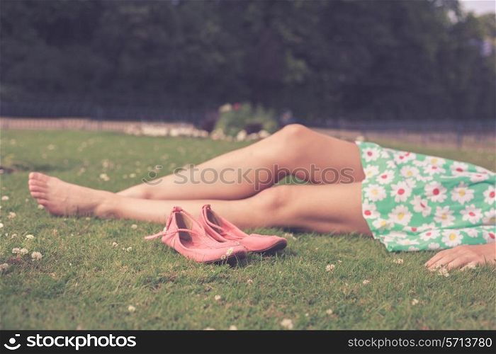 The bare legs of a young woman as she is relaxing on the grass in a park