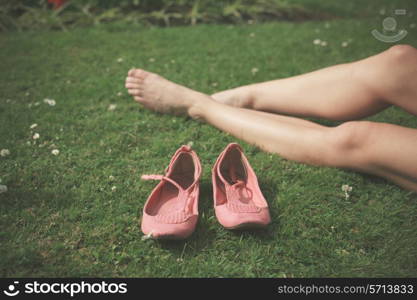 The bare legs of a young woman as she is relaxing on the grass in a park