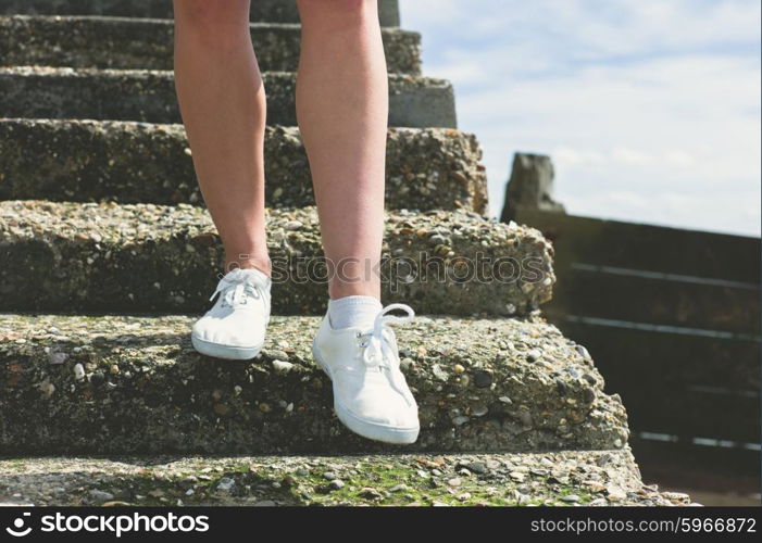 The bare legs of a young woman as she is walking down some steps on the beach